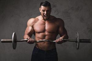 massiccio brutale bodybuilder fare esercizi con manubrio foto