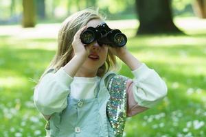 carino poco ragazza con un' retrò binocolo nel un' città parco foto