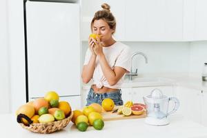 bellissimo donna annusando fresco arancia durante agrume succo preparazione a casa foto