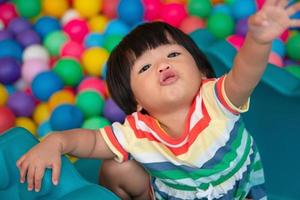 contento asiatico ragazza uno e metà anni olds giocando poco colorato palle nel piscina sfera. il concetto di giocando è il migliore apprendimento per bambini. foto