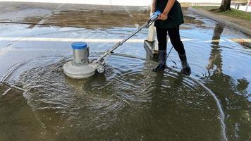 dipendenti uso un' calcestruzzo pavimento scrubber nel il ufficio parcheggio quantità. casa o Hotel pulito il esterno pavimento con un' scrubber e chimico soluzione. commerciale attività commerciale Servizi foto