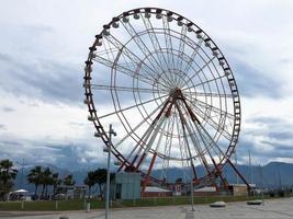 un' grande il giro bellissimo Ferris ruota, un' panoramico piattaforma nel un' parco su un' tropicale mare caldo estate ricorrere con palma alberi contro un' blu cielo foto