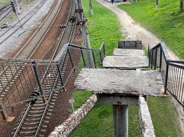 vecchio collassata passaggi di un' alto ferrovia ponte con buchi. rotto pericoloso ponte richiedendo urgente riparazione e chiusura foto