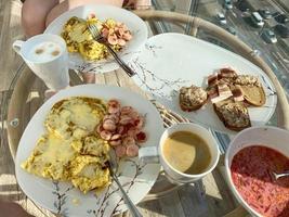 un' bellissimo sostanzioso e salutare mattina prima colazione con un uovo frittata, caffè e panini su piatti e tazze su un' bicchiere tavolo foto