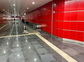 grande rosso moderno lungo luminosa metropolitana passerella fra la metropolitana stazioni con viaggio camminatori e scale mobili per Presto passaggio di viaggiatori foto