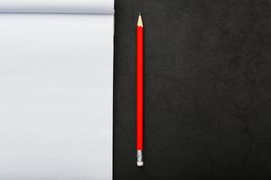 bloc notes con un' rosso matita su un' nero pietra piatto sfondo, per formazione scolastica, registrazione obiettivi e fatti foto