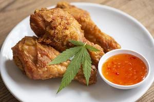 cannabis cibo natura erba concetto, coscia di pollo fritta su piatto con salsa di immersione di pollo, cibo di pollo fritto croccante con foglia di cannabis - pianta di foglie di marijuana foto