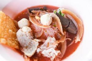 noodles con frutti di mare su zuppa rossa - cibo tailandese caldo e piccante noodle calamari carne di maiale palla di pesce gloria mattutina croccanti wonton pelle di maiale e cubetti di sangue foto