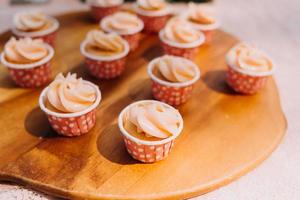 buongustaio cupcakes con bianca buttercream glassa e spruzzatori su di legno sfondo foto