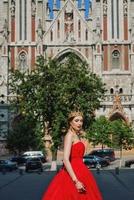 bellissimo donna nel lungo rosso vestito e nel reale corona quasi cattolico Cattedrale foto