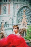 bellissimo donna nel lungo rosso vestito e nel reale corona quasi cattolico Cattedrale foto