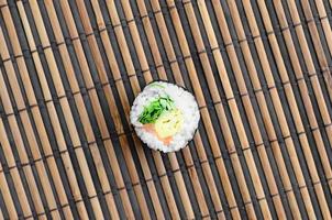 Sushi rotolo menzogna su un' bambù cannuccia servire stuoia. tradizionale asiatico cibo. superiore Visualizza. piatto posare minimalismo tiro con copia spazio foto