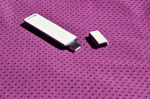 un' moderno portatile USB Wi-Fi adattatore è posto su il viola abbigliamento sportivo fatto di poliestere nylon fibra foto