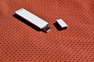 un' moderno portatile USB Wi-Fi adattatore è posto su il rosso abbigliamento sportivo fatto di poliestere nylon fibra foto