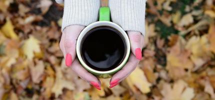 donna indossare bianca maglione Tenere un' verde caffè tazza foto