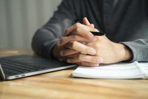 primo piano delle mani giunte dell'uomo serrate insieme sul tavolo, uomo d'affari che si prepara per il colloquio di lavoro, concentrazione prima di negoziati importanti, pensiero o decisione, concetto di business foto