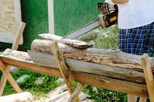 motosega nel il mani di un' lavoratore taglio legna da ardere, avvicinamento foto