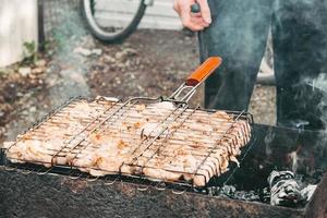 uomo patatine fritte marinato pollo su un' metallo griglia. pollo kebab foto