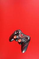 un' nero telecomando da gioco gioco controllore si libra isolato su un' rosso sfondo. interattivo divertimento foto