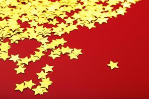 oro stelle su rosso sfondo. il concetto di saluto carte, titoli e ragnatela luogo. un' dispersione di d'oro stelle foto