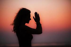 sportivo donna praticante yoga nel il parco a tramonto - fabbricazione mano saluto namaste. tramonto luce, d'oro ora, lente razzi. la libertà foto