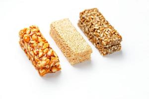 grano muesli bar con arachidi, sesamo e semi nel un' riga su un' bianca sfondo. superiore Visualizza tre assortito barre, isolato foto