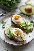 pane tostato, uova sode, fetta di avocado, microgreens su un piatto foto