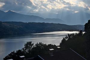 luce del sole è toccante il acqua di il lago millstätter vedere nel Austria con montagne di il Alpi nel il sfondo. panoramico paesaggio su un' nuvoloso giorno foto