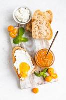 affettato artigiano fatti in casa pane con ricotta o Villetta formaggio e arancia marmellata su leggero sfondo. gustoso prima colazione. alto chiave fotografia. foto