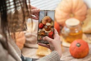 ragazza assunzione foto di zucche, autunno le foglie e teiera su un' finestra. ragazza Fotografare su Telefono rustico Halloween composizione. contento ringraziamento e Halloween