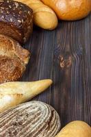 assortimento di al forno pane su buio di legno sfondo. forno e drogheria cibo memorizzare concetto. piatto posare con spazio per testo foto