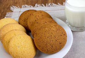 cibo, cibo spazzatura, culinario, cottura al forno e mangiare concetto - vicino su fiocchi d'avena biscotti e latte bicchiere foto