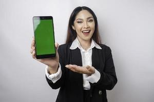 un' contento giovane donna d'affari è indossare nero completo da uomo, mostrando copia spazio su sua Telefono isolato di bianca sfondo foto