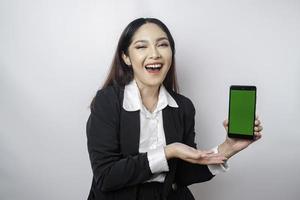 un' contento giovane donna d'affari è indossare nero completo da uomo, mostrando copia spazio su sua Telefono isolato di bianca sfondo foto
