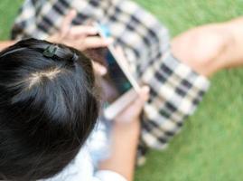 alunno giocando gioco su smartphone su il scuola cortile foto