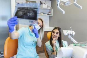 mascella scansione è essere spiegato di il dentista per il paziente. . indossare protettivo maschere rispetto il prescritto sicurezza le misure per quanto riguarda il covid-19 pandemia. foto