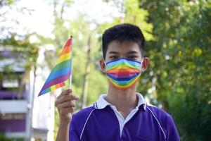 ritratto asiatico giovane ragazzo detiene arcobaleno bandiera, lgbt simbolo, nel mani mentre unendo il suo lgbt attività a scuola, concetto per lgbt Comunità celebrazione nel orgoglio mese, giugno, 2023, in giro il mondo. foto