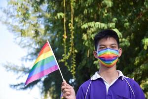 ritratto asiatico giovane ragazzo detiene arcobaleno bandiera, lgbt simbolo, nel mani mentre unendo il suo lgbt attività a scuola, concetto per lgbt Comunità celebrazione nel orgoglio mese, giugno, 2023, in giro il mondo. foto