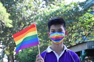 ritratto asiatico giovane ragazzo detiene arcobaleno bandiera, lgbt simbolo, nel mani mentre unendo il suo lgbt attività a scuola, concetto per lgbt Comunità celebrazione nel orgoglio mese, giugno, 2023, in giro il mondo. foto