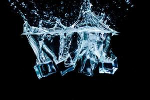 ghiaccio cubi nel acqua con bolle su nero sfondo foto