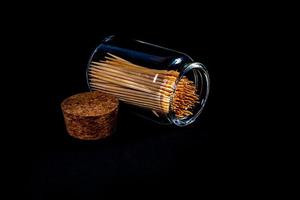 bambù di legno stuzzicadenti nel bicchiere barattolo, vino bicchiere. nel benna. stuzzicadenti su nero sfondo. davanti Visualizza stuzzicadenti, caduto a partire dal mano, posto per testo, foto