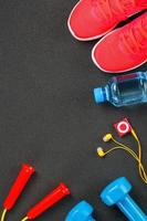 superiore Visualizza di gli sport attrezzatura, manubri, un' saltare corda, un' bottiglia di acqua, scarpe da ginnastica e un' giocatore. isolato su un' grigio foto