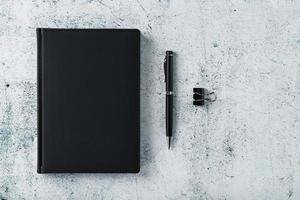 ufficio scrivania con nero bloc notes e penna su grigio sfondo. superiore Visualizza con copia spazio. foto