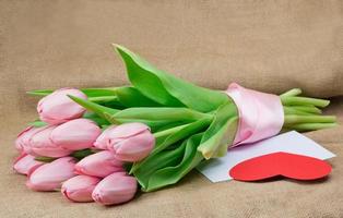bouquet di tulipani rosa con nastro di raso, busta e cuore foto
