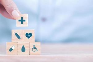 l'uomo d'affari sceglie un simbolo medico sanitario delle icone di emoticon sul blocco di legno, sul concetto di assicurazione sanitaria e medica foto