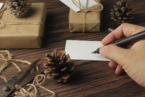 maschio mani involucro nuovo anno i regali e scrittura carte su un' Marrone di legno tavolo. foto