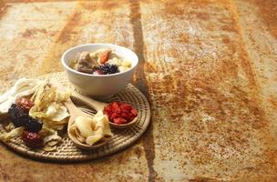 Cinese tradizionale nutriente salutare cibo - un' bianca ciotola di chiaro la minestra con Cinese erbaceo medicina - ginseng, bacche di goji isolato su metallo sfondo. foto