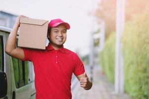 giovane uomo contento trasporto pacco nel postale consegna Corriere nel consegna pacchetto. foto