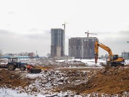 costruzione di grattacielo edifici nel inverno. il opera di escavatori. terra lavori. scavando pozzi. calcestruzzo edificio montatura foto