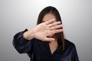 donna nel nero completo da uomo mostrando sua rifiuto con no su sua mano contro grigio sfondo foto